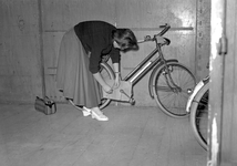 837017 Afbeelding van een vrouw die haar fiets gereedmaakt voor verzending per trein op het N.S.-station Amsterdam ...